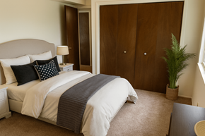 East Lansing apartment for rent - A bedroom with a large bed and a potted plant.