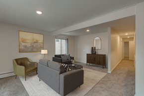 East Lansing apartment for rent - A living room with a grey couch, a green chair, and a painting on the wall.
