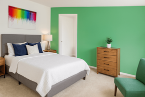 East Lansing apartment for rent - A bedroom with a bed, nightstand, and chair.