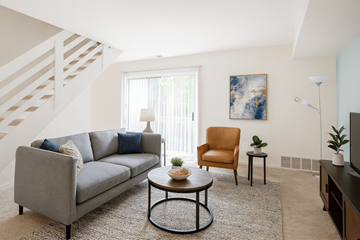 East Lansing apartment for rent - A living room with a grey couch, a brown chair, a coffee table, and a painting on the wall.