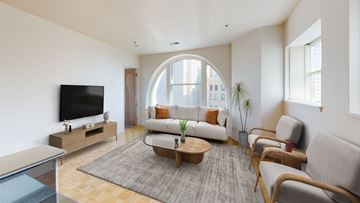 Detroit apartment for rent - a living room with a large arched window and a couch