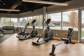 Troy apartment for rent - A gym with a row of exercise bikes and a bench with dumbbells.