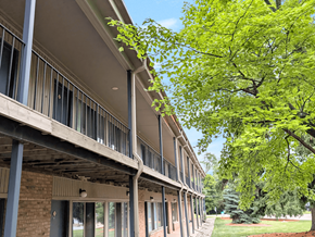 Okemos apartment for rent - A row of apartment buildings with balconies and trees in the background.