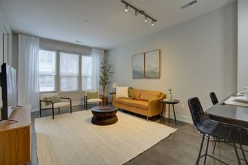 Lansing apartment for rent - A living room with a yellow couch and a television.