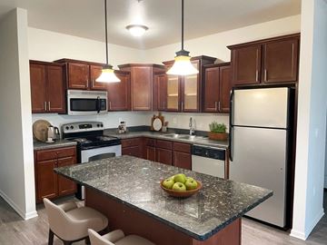 Okemos apartment for rent - a kitchen with wooden cabinets and stainless steel appliances and a granite counter top