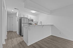 Lansing apartment for rent - the kitchen and living room in a renovated apartment with white walls and wood flooring
