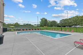 Northville apartment for rent - a swimming pool with chairs around it and a grassy field in the background