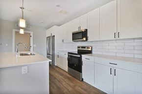 Troy apartment for rent - A kitchen with white cabinets and a black microwave above the stove.
