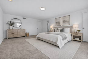 Farmington Hills apartment for rent - A bedroom with a large bed, a dresser, and a mirror.