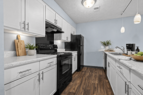 Lansing apartment for rent - A kitchen with black appliances and white cabinets.