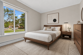 Livonia apartment for rent - A bedroom with a large bed and a window overlooking a green area.