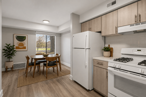 Northville apartment for rent - A kitchen with a white refrigerator, a dining table with chairs, and a stove top oven.