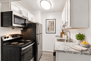 Plymouth apartment for rent - A black and white kitchen with a stove, microwave, and refrigerator.