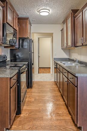 Lansing apartment for rent - a kitchen with wooden cabinets and black appliances