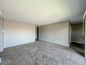 Roseville townhouse for rent - an empty living room with a carpeted floor and a hallway in the background