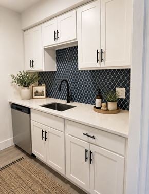 Clinton Twp apartment for rent - A kitchen with white cabinets and a black and white tiled backsplash.