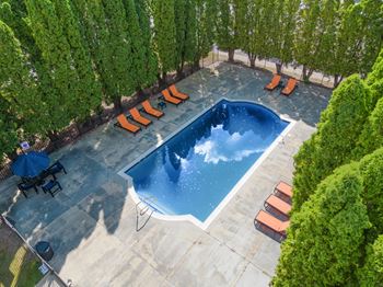 A pool of water in a backyard with orange chairs