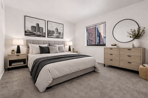 Detroit apartment for rent - A bedroom with a large bed, a nightstand with a lamp, and a framed picture on the wall.