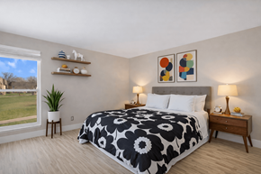 Rochester Hills apartment for rent - A bedroom with a large bed and a view of a grassy area outside the window. at Rochester Club Apartments, Rochester, 48306
