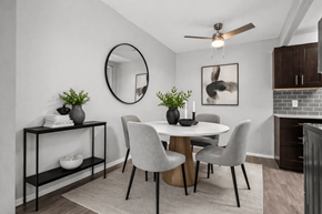 Plymouth apartment for rent - A dining room with a round mirror, a white table, and grey chairs.