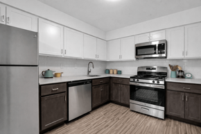 Rochester Hills apartment for rent - A kitchen with white cabinets and a stainless steel refrigerator. at Rochester Club Apartments, Apartments, Rochester, MI