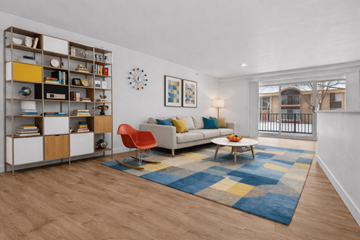 Southfield apartment for rent - A living room with a white sofa, a red chair, a wooden coffee table, and a bookshelf with various items.