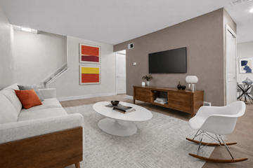 Canton townhouse for rent - A modern living room with a white sofa, a white coffee table, a white rocking chair, a wooden cabinet, a flat screen TV, and a painting on the wall.