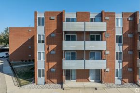 Royal Oak apartment for rent - A red brick building with a white van parked in front. at The Park on 13 Apartments - Royal Oak, MI Apartments, Royal Oak