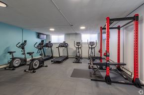 Royal Oak apartment for rent - A gym with exercise equipment including stationary bikes, rowing machines, and a squat rack. at The Park on 13 Apartments - Royal Oak, MI Apartments, Royal Oak, Michigan