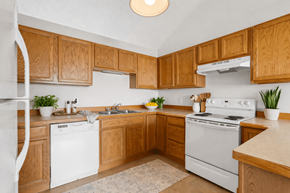 Saginaw townhouse for rent - A kitchen with wooden cabinets and white appliances.