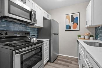 A modern kitchen with a stainless steel refrigerator, oven, and microwave.