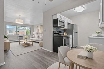 A modern kitchen with a dining table set with a vase of flowers and a book.