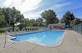 Madison Heights apartment for rent - A large outdoor swimming pool surrounded by a fence and lounge chairs.