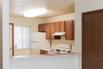 Ottumwa apartment for rent - A kitchen with wooden cabinets and a white stove top oven.