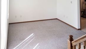 Ottumwa apartment for rent - A room with a carpeted floor and a wooden staircase.