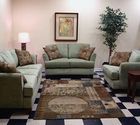 Oskaloosa apartment for rent - A living room with a green couch, a brown and white rug, and a green armchair.