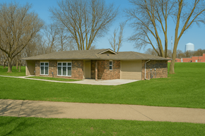 Des Moines triplex for rent - A house with a brown roof and a green lawn in front.