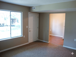 Columbus Junction apartment for rent - A room with a carpeted floor, a door, and a window.