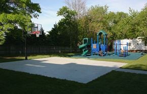 Ames townhouse for rent - A basketball court with a basketball hoop and a playground with slides in the background.