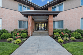 Des Moines apartment for rent - A building entrance with a concrete pathway and a brick pillar.