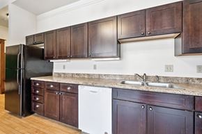 Oskaloosa apartment for rent - A kitchen with dark wood cabinets and a black refrigerator.