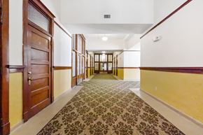 Oskaloosa apartment for rent - A hallway with a patterned carpet and wooden doors.