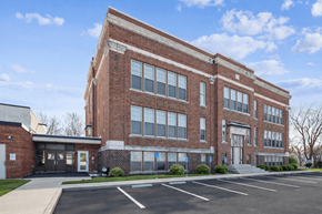 Oskaloosa apartment for rent - A large red brick building with a parking lot in front.