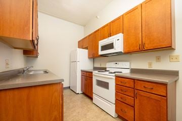 Sioux City apartment for rent - A kitchen with wooden cabinets and white appliances.