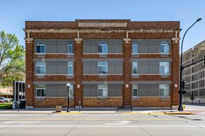 Sioux City apartment for rent - A large brick building with many windows is on a street corner.