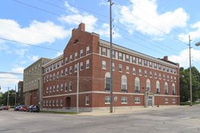 Mason City apartment for rent - A large red brick building with a parking lot in front.