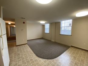 Mason City apartment for rent - A spacious room with a carpeted area in the center and a door to the left.