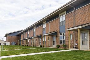 Spencer apartment for rent - A long brick building with a white trim around the windows and doors.
