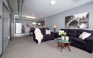 Spencer apartment for rent - A living room with a black couch, a coffee table, and a painting on the wall.
