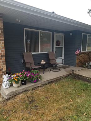 Spencer apartment for rent - A house with a blue siding and a porch with two chairs and a table.